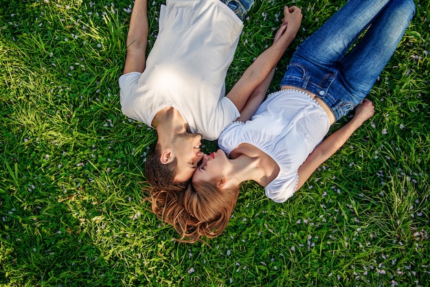 Romantisch paar jonge mensen die op gras in park liggen.