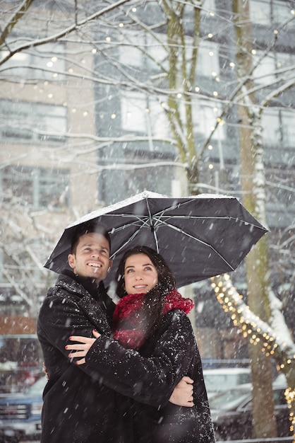 Romantisch paar omarmen in straat tijdens sneeuwval