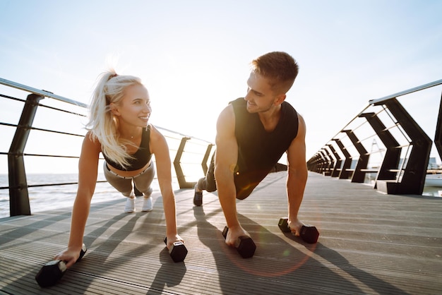 Romantisch paar samen sporten op strand pier Twee sportieve atleten doen warming-up excersises