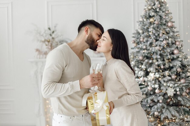 Romantisch paar staande in de buurt van kerstboom met glazen champagne