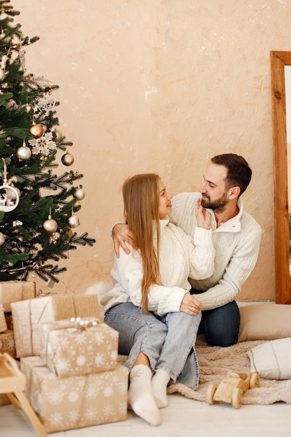 Romantisch paar zittend op een vloer bij de kerstboom thuis