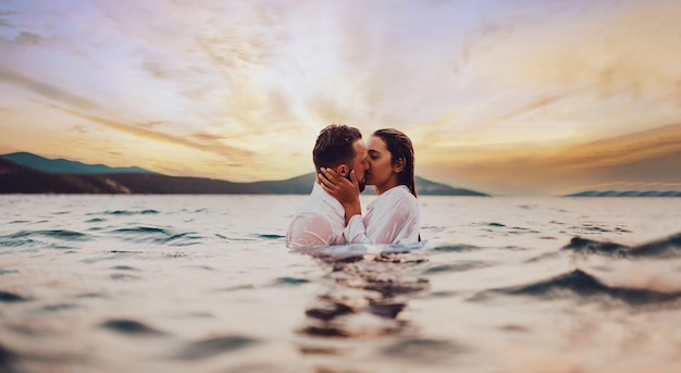 Romantisch paar zoenen in de zee bij zonsondergang foto van hoge kwaliteit