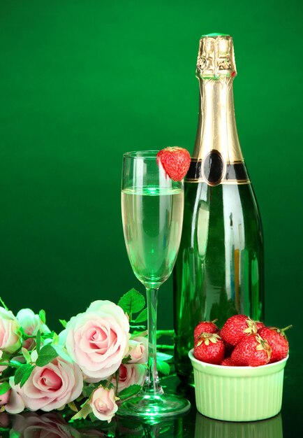 Romantisch stilleven met champagne, aardbei en roze rozen, op donkere kleurenachtergrond