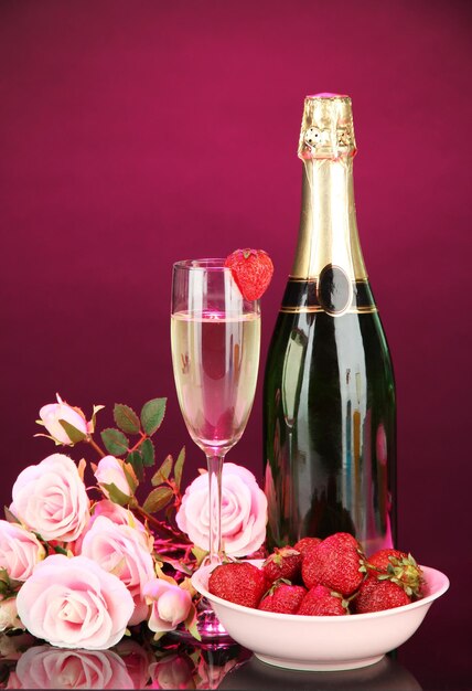 Romantisch stilleven met champagne, aardbei en roze rozen, op donkere kleurenachtergrond