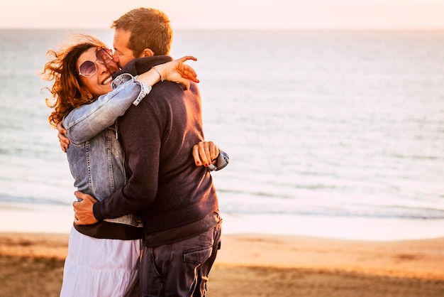 Romantisch volwassen paar in liefde knuffel en veel plezier samen met vrolijke Concept van relatie man en vrouw omarmen buiten met strand en oceaan op achtergrond zonsondergang licht en mensen zoenen