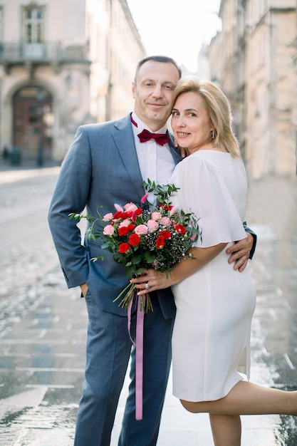 Romantisch volwassen paar in oude Europese stad. Close-up portret van knappe 50-jarige man en zijn mooie charmante vrouw verliefd, staande op straat en glimlachend in de camera