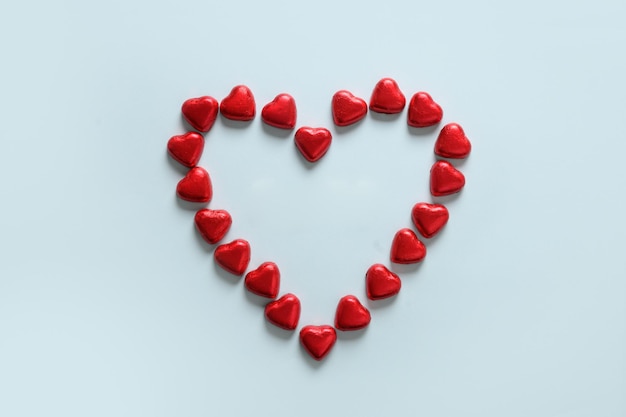Romantische chocoladesnoepjes als hart in rode folie en tekst op houten blokken - Liefde in witte plaat.
