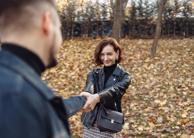 Romantische date. Een jong stel geliefden houdt hand in hand op de achtergrond van gevallen herfstbladeren. Volg mij