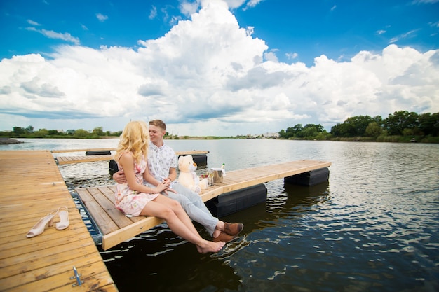 Romantische date verrassing. Een jonge man en een meisje op een houten pier. Knuffel en kus zittend op de pier. Romantisch liefdesverhaal