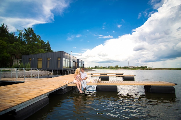 Foto romantische date verrassing. een jonge man en een vrouw op een houten pier. knuffel en kus zittend op de pier. romantisch liefdesverhaal