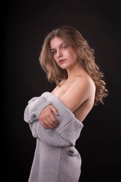 Romantische jonge vrouw poseren in trui met blote schouders