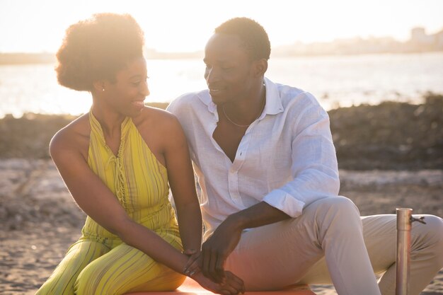 Romantische jonge zwarte paar man en vrouw glimlachen en genieten van tijd doorbrengen vrije tijd samen met strand en zonsondergang op de achtergrond, gelukkige toeristische levensstijl mensen buiten met zonlicht