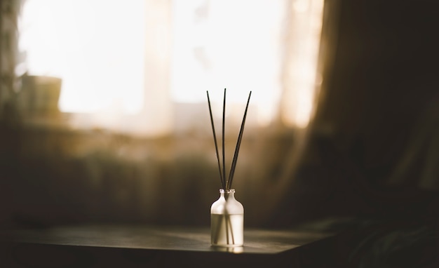 Foto romantische kaars met aromatherapiestokjes en decoratieve boomtak in prachtig donker avondlicht