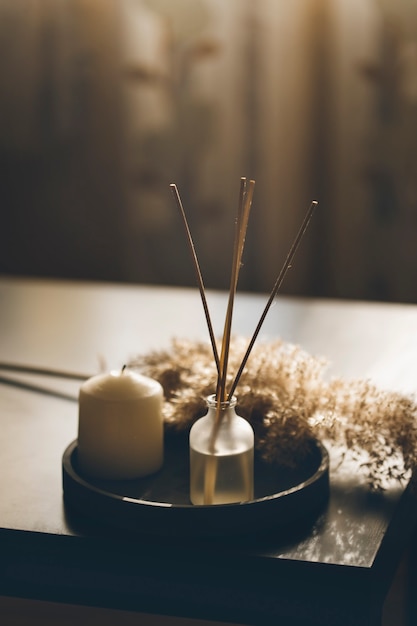 Romantische kaars met aromatherapiestokjes en decoratieve boomtak in prachtig donker avondlicht