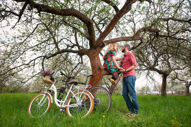 Romantische liefhebbers in de buurt van de boom en fietsen in de lentetuin