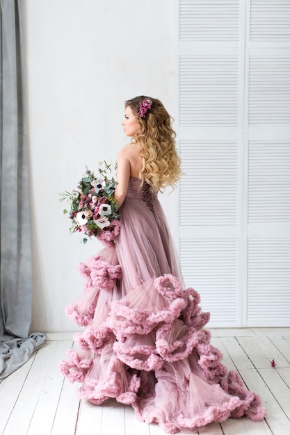 Romantische mode vrouw in een roze jurk en boeket.