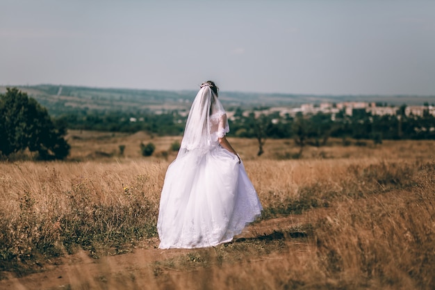 Romantische mooie bruid. Vrouw in een trouwjurk loopt over het veld