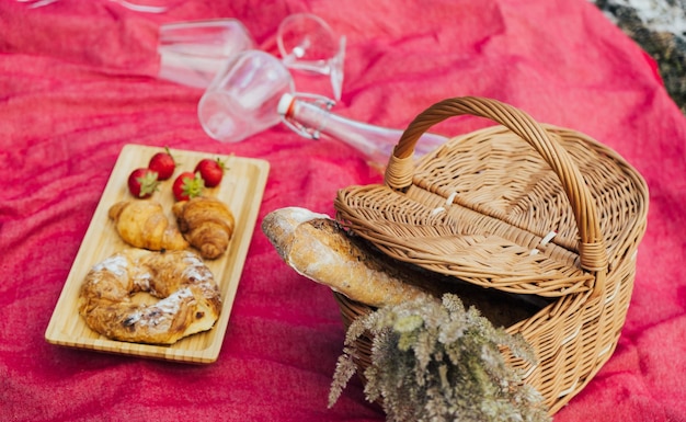 Romantische picknick met mand met stokbrood en zomerbloemen witte wijn en croissants