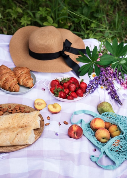 Romantische picknickscène op de zomerdag. Outdoor picknick met wijn en fruit in de open lucht op de achtergrond van groen gras.