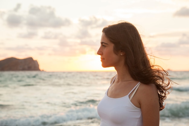 Romantische vrouw die zich vrij voelt op een zonsondergangstrand in Ibiza