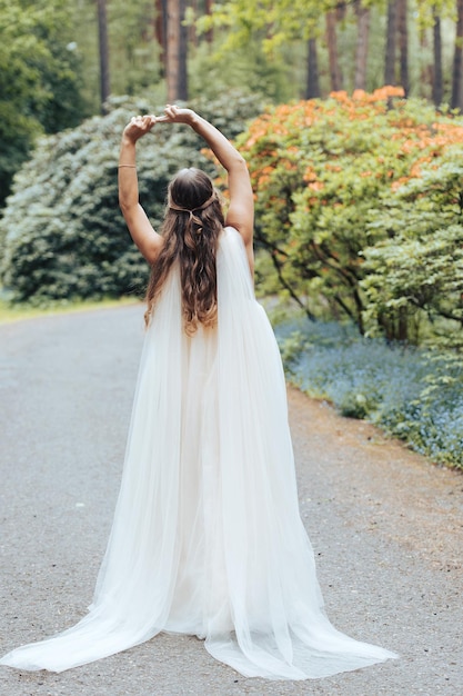 Romantische vrouw in een luxe jurk dansend in een bloeiend rododendronpark