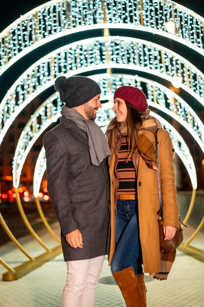 Romantische winterblindheid van een Kaukasisch stel naast de kerstverlichting van de stad