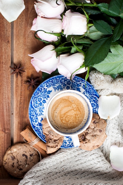 Romatic coffee in a cup on a wooden background with a plaid, a bouquet of white roses and autumn coziness. good morning. upper view. copy spase