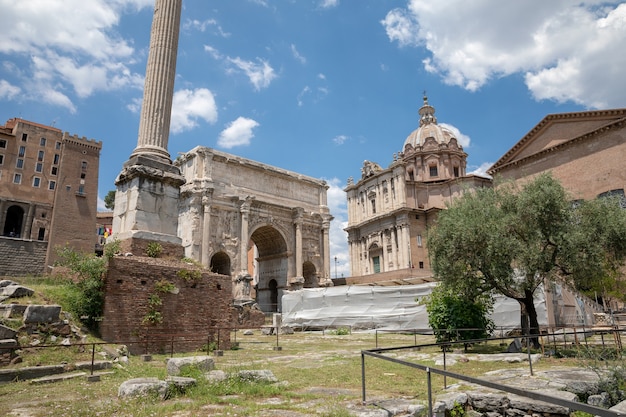 Rome, Italy - June 20, 2018: Panoramic view of Roman forum, also known by Forum Romanum or Foro Romano. It is a forum surrounded by ruins of ancient government buildings at center of city of Rome