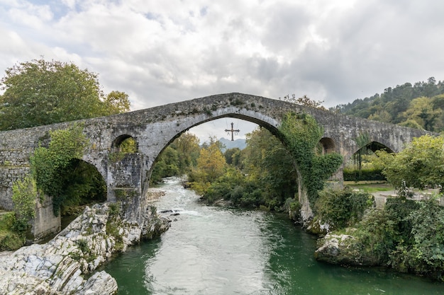 Foto romeinse brug in de stad cangas de onis, spanje met het overwinningskruis dat aan de boog hangt.