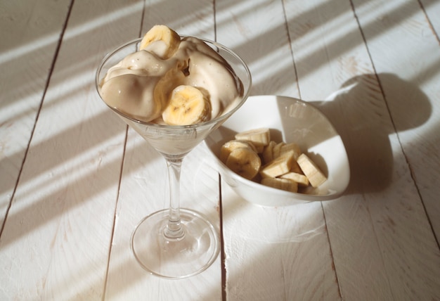 Romig bananenroomijs met stukjes fruit op houten tafel