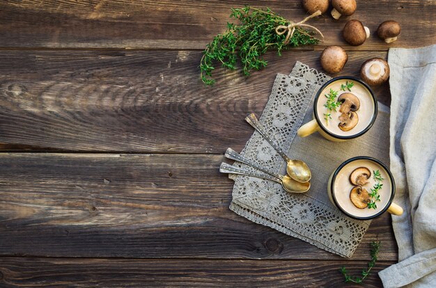 Romige champignonsoep met champignons in mokken op rustieke houten achtergrond Bovenaanzicht Kopieer ruimte