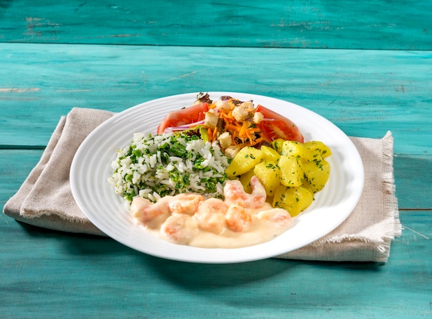 Romige garnalen garnalen met tomaten wortelen aardappelen en rijst met broccoli op houten tafel