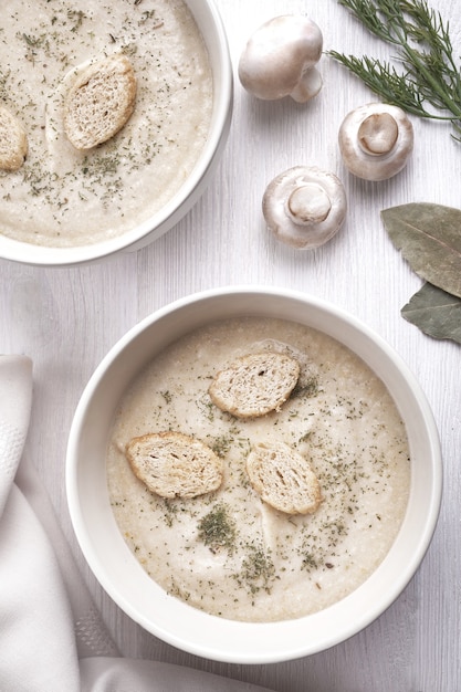 Foto romige kippensoep met champignons op een witte plaat.