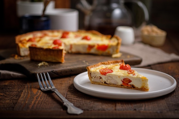 Romige shortbread taart quiche met kerstomaatjes en kip in het dorp op een houten tafel