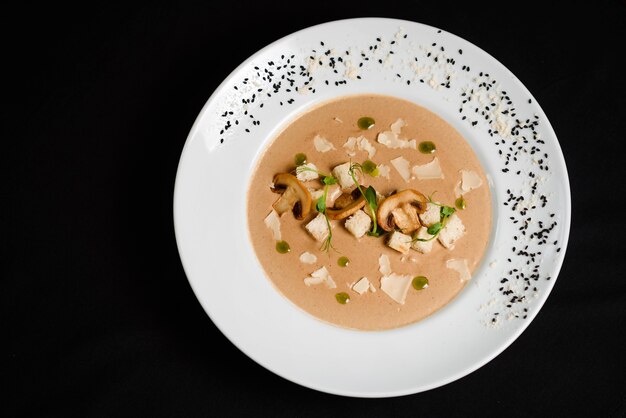 Romige soep met champignons en croutons op zwarte tafel