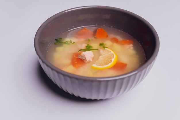 Romige soep met zalm in kom en sneetjes roggebrood op een grijze gestructureerde achtergrond selectieve focus