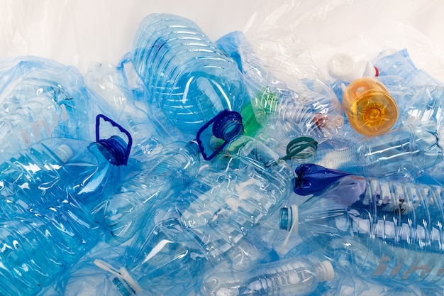 Rommelende omgeving. Flessen van verschillende maten en kleuren die bij elkaar op een blauwe plastic mat worden geplaatst en vervuiling veroorzaken