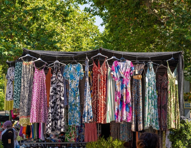Rommelmarktkraam met dameskleding op een markt alle kleurrijke en bloemrijke jurken hangen
