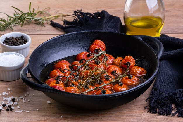 Ron braadpan met gekonfijte tomaten op houten tafel.