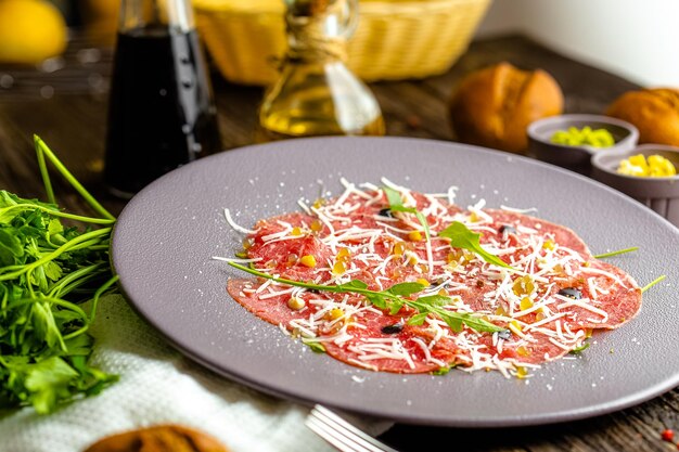 rond bord, voorgerecht Stroganina van gemarmerd rundvlees met geitenkaas en kaviaar, vleeswaren