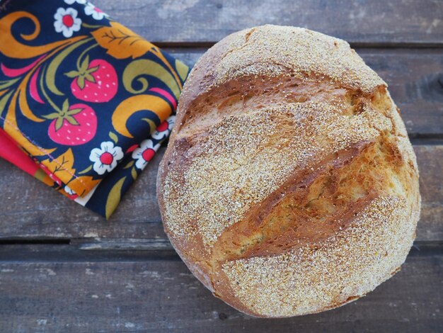Foto rond brood bovenaanzicht heerlijk vers maisbrood op een houten tafel en een mooie traditionele handdoek