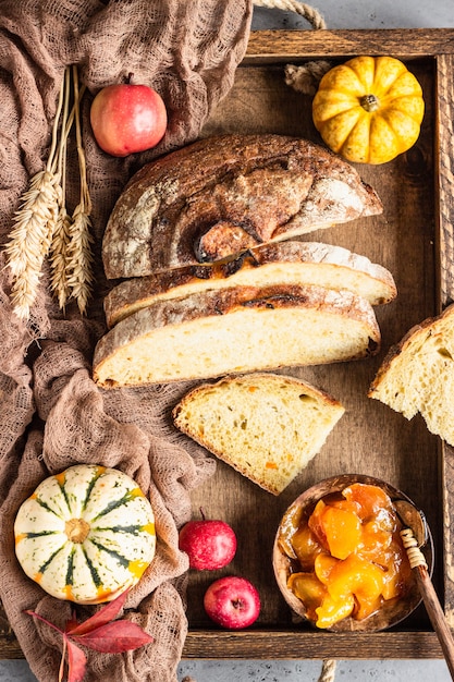 Rond brood van artisanaal tarwebrood met pompoen en appel in een houten dienblad.