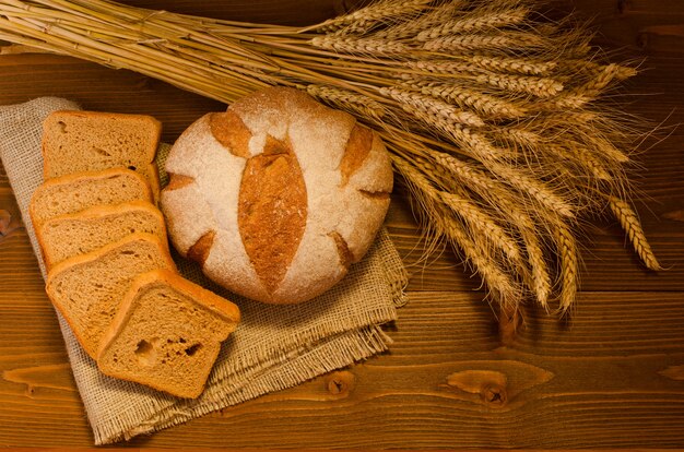 Rond en vierkant roggebrood op een plundering, een schoof op houten tafel