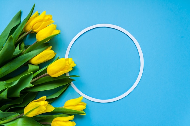 Rond kader en gele tulpen op blauwe copyspaceachtergrond