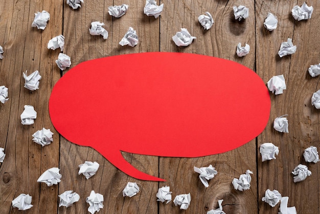 Foto rond tekstballon op de vloer af met belangrijke informatie erin geschreven met papieren wikkels rond dialoogballon op de grond met cruciaal nieuws erin en verfrommelde aantekeningen overal