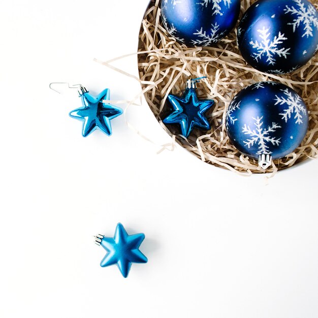 Ronde doos met heldere blauwe kerstballen op witte achtergrond.