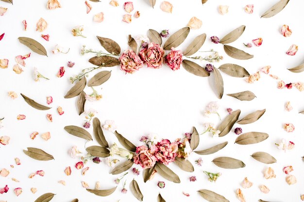 Ronde frame krans patroon met rozen, roze bloemknoppen, takken en gedroogde bladeren op wit oppervlak
