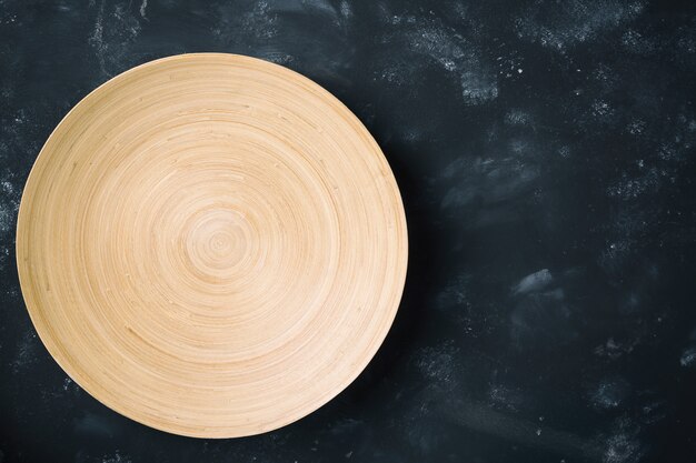 Ronde houten plaat op zwarte stenen tafel met witte vlekken