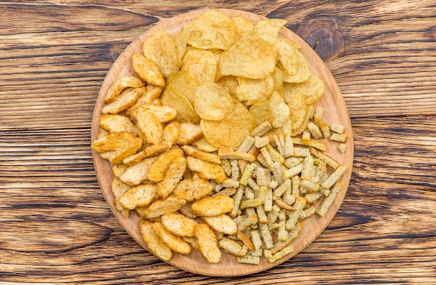 Ronde houten plank met droge zoute snacks voor bier op tafel Bovenaanzicht