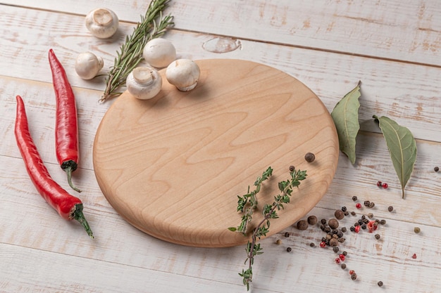 Ronde houten snijplank met lege ruimte, champignons, chilipeper en specerijen op een witte achtergrond met kopieerruimte voor tekstzijaanzicht